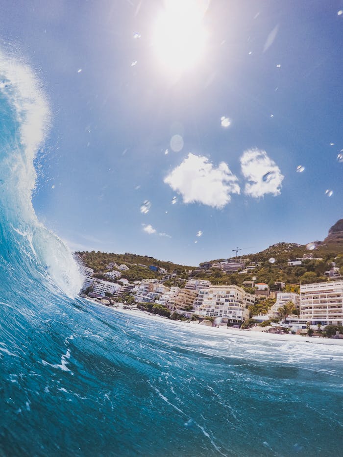 experience-img Dynamic view of ocean waves crashing near Cape Towns coastal buildings under a bright blue sky.